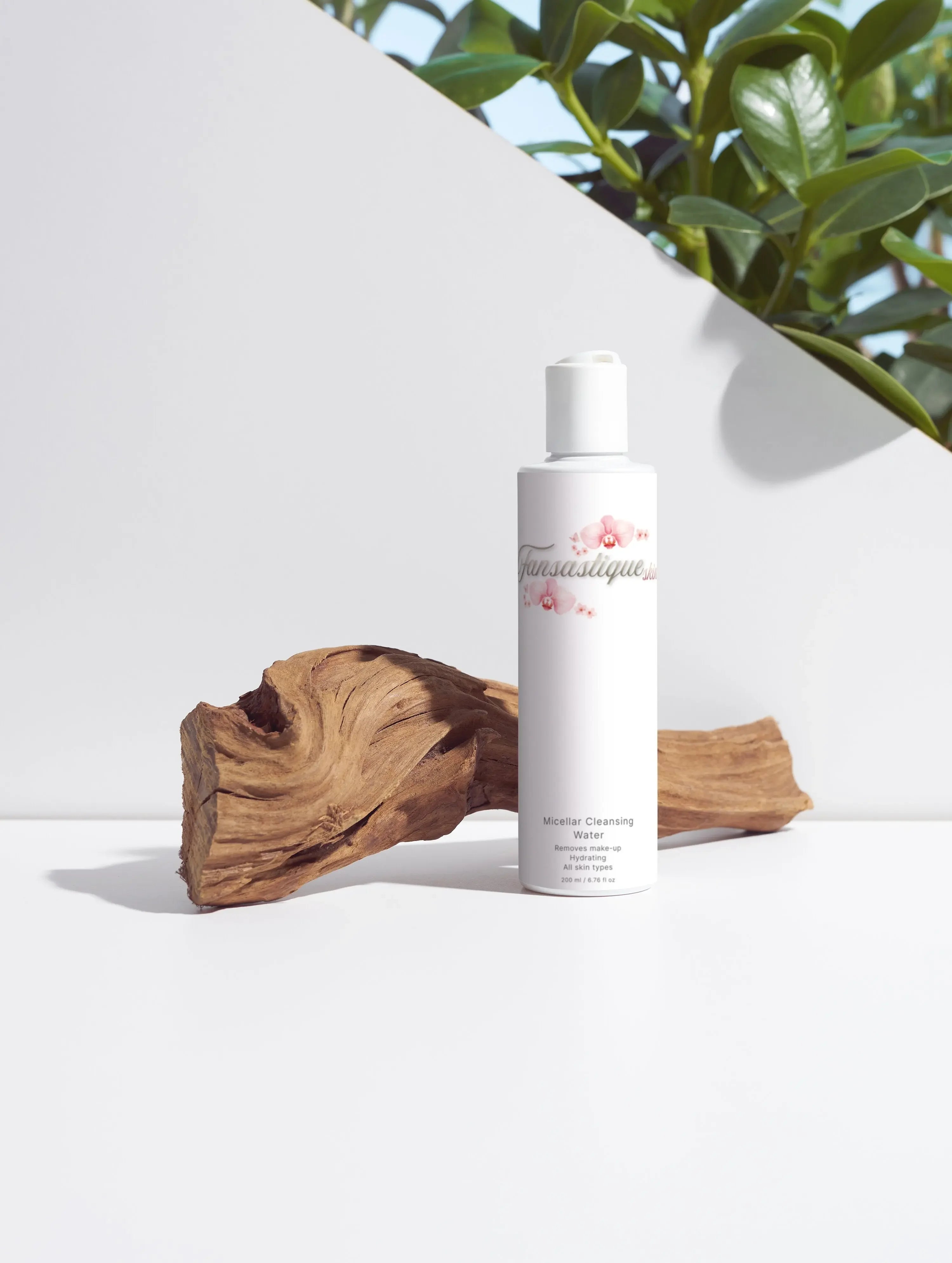Micellar cleansing water fles voor de huidverzorging, met hout en groene bladeren op de achtergrond.